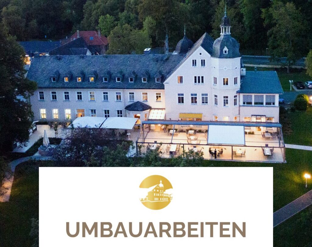 Alt-Text: Luftaufnahme eines historischen Gebäudes mit modernem Anbau und Terrasse, umgeben von Bäumen, im Hintergrund ist der Schriftzug "UMBAUARBEITEN" zu sehen.