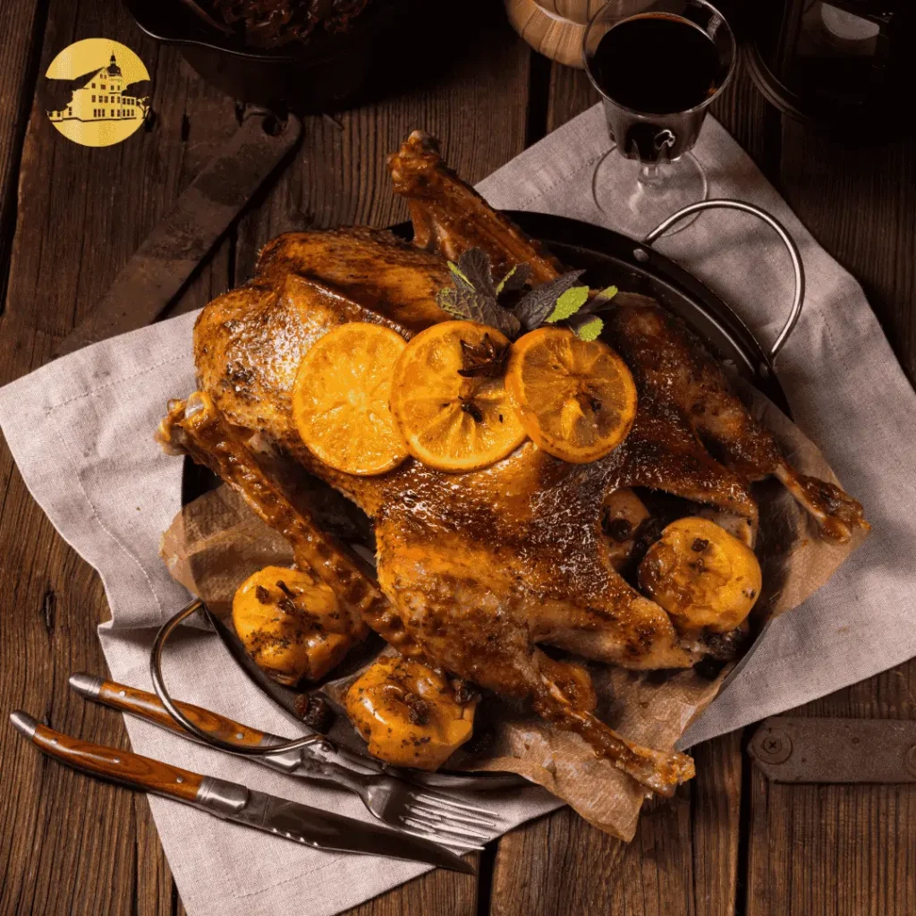 Eine Gans fertig aus dem Ofen liegt auf einem Teller, mit Orangen Scheiben garniert