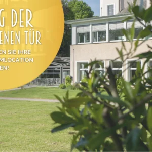 Yellow banner with the words ‘Open Day – Discover your dream location!’ in front of a modern building with large windows. In the foreground, green plants frame a well-tended lawn. In the background, blue sky stretches above the trees.